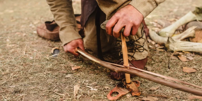 Someone using a bow drill to start a fire