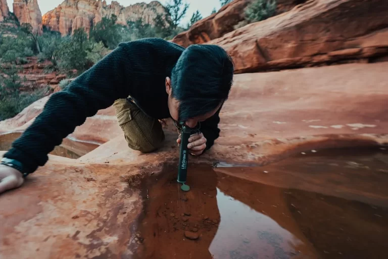man drinking through portable water filter